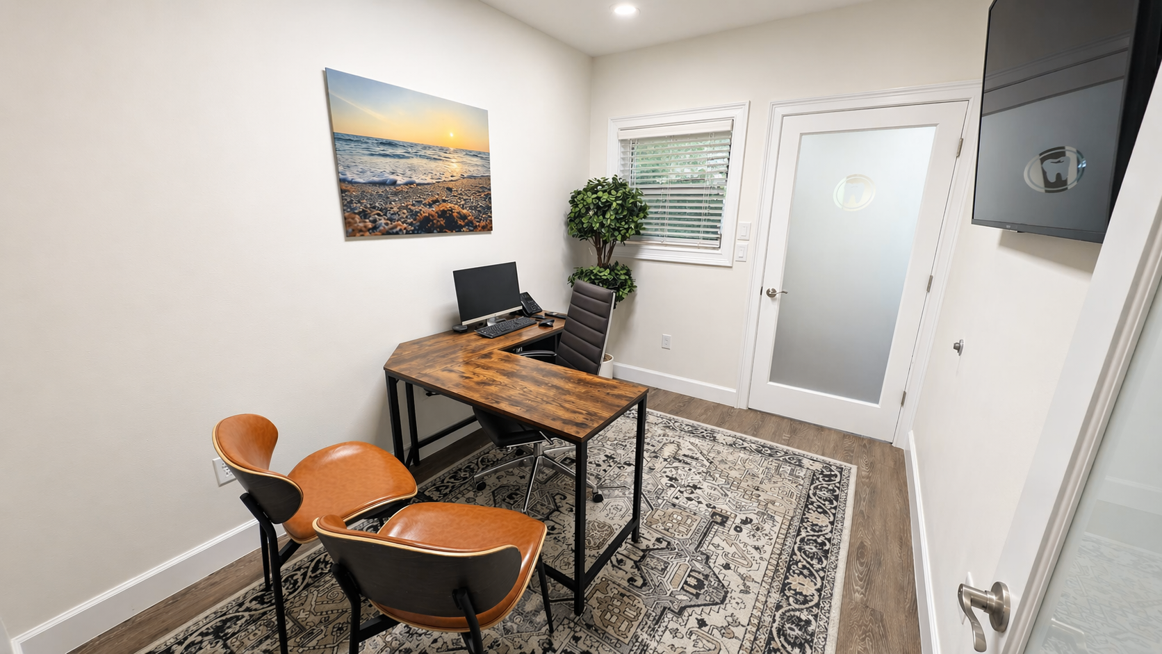 Private consultation room with leather chairs, a wood desk, and a coastal art print