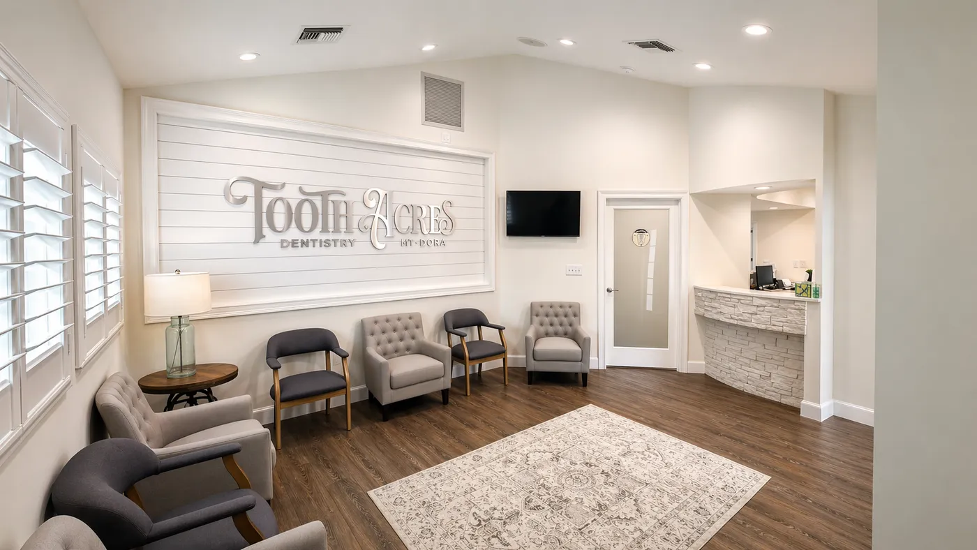 The Tooth Acres Dentistry waiting lounge — soft taupe armchairs, shiplap accent wall with the brand mark, and warm wood floors