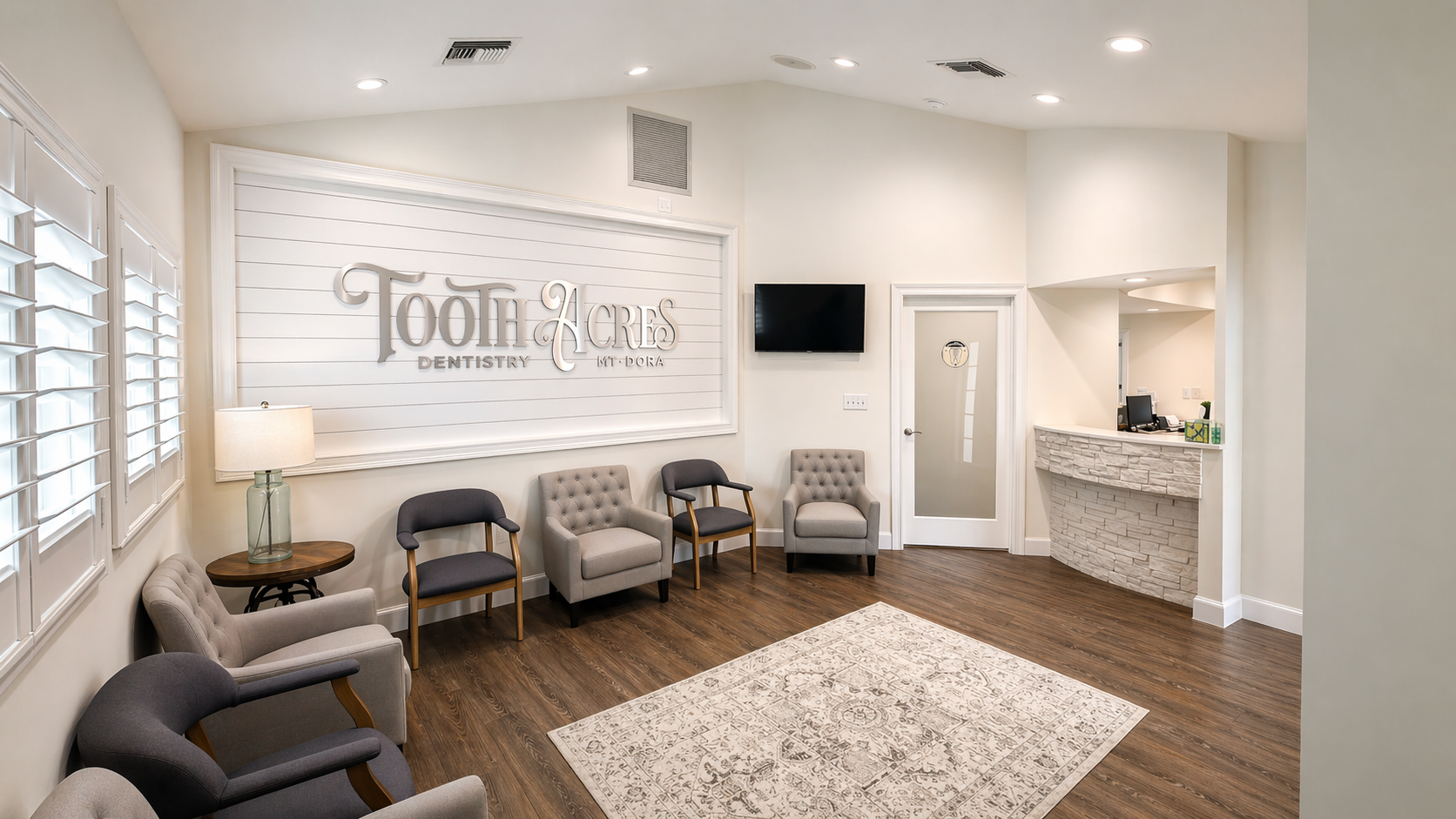 The Tooth Acres Dentistry waiting lounge — soft taupe armchairs, shiplap accent wall with the brand mark, and warm wood floors